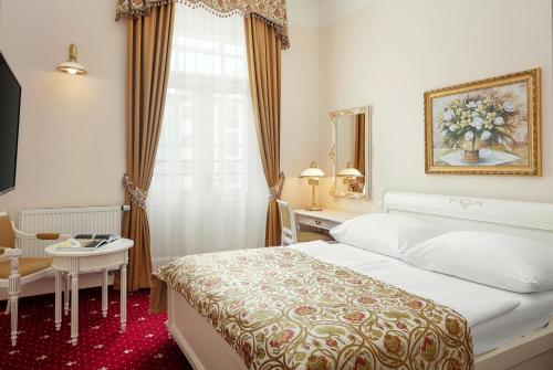 プラハにあるアルクシュ ダウンタウン ホテルのベッド、テーブル、鏡が備わる客室です。