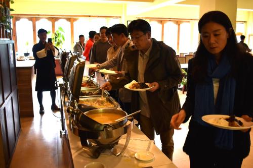 eine Gruppe von Personen, die Teller mit Speisen am Buffet halten in der Unterkunft Whispering Woods Resort in Thimphu