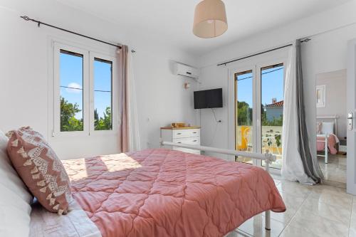a bedroom with a large bed and two windows at Villa Santa Marina in Spetses