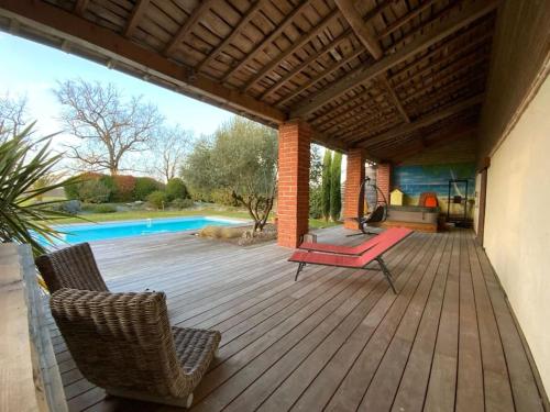 une terrasse avec un banc et des chaises rouges ainsi qu'une piscine dans l'établissement Logement familial « Le Ribet », à Saint-Étienne-de-Tulmont