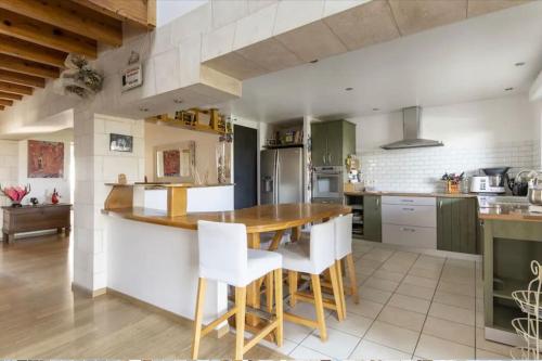 - une cuisine avec une table en bois et des chaises blanches dans l'établissement Logement familial « Le Ribet », à Saint-Étienne-de-Tulmont