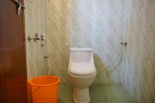a bathroom with a toilet and an orange bucket at Classiyo Green Mount Resort in Chinnakanal