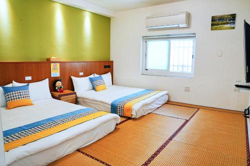 duas camas num quarto com paredes verdes em The Wind B&B em Budai