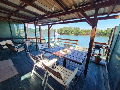 a wooden deck with a table and chairs on the water at Ada Bojana - Kucica Djakonovic in Ulcinj