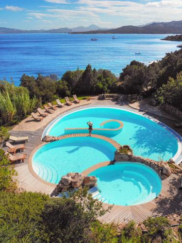 an infinity pool with chairs and the ocean in the background at Hotel Capo d'Orso Thalasso & SPA in Palau