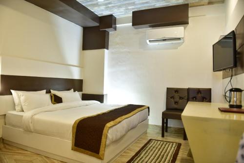 a bedroom with a bed and a desk and a tv at Hotel Pinnacle in Dehradun