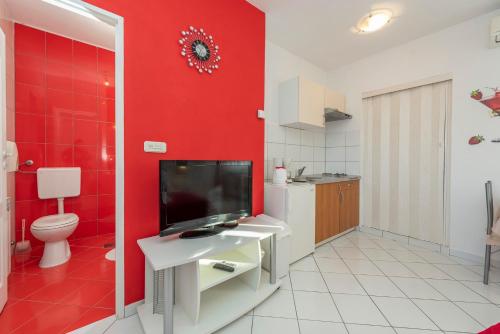 La salle de bains rouge est pourvue de toilettes et d'une télévision murale. dans l'établissement Villa Toni - Adriatic Luxury Villas, à Zadar