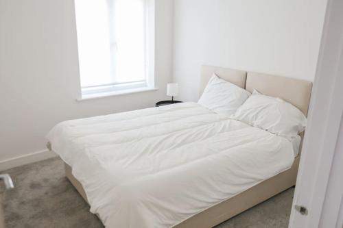 un letto bianco in una camera bianca con finestra di Peaceful 2 Bed Townhouse, Close to City Centre a Reading