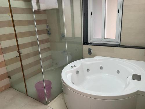 uma banheira branca na casa de banho com um chuveiro em Royal Nest Premium-AS em Pune