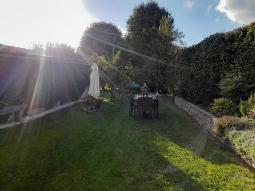 einen Garten mit einem Tisch und einem Regenschirm im Gras in der Unterkunft Le Gai Pinson in Beausaint