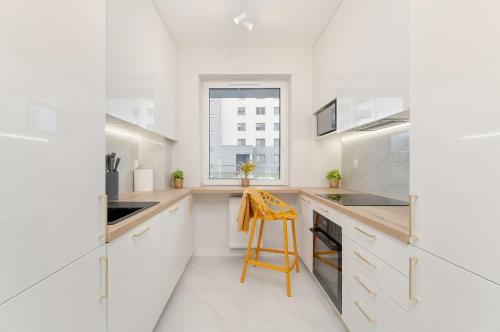 cocina con armarios blancos y taburete amarillo en Bright Apartment with Spacious Balcony and Air Conditioning by Renters, en Rzeszów