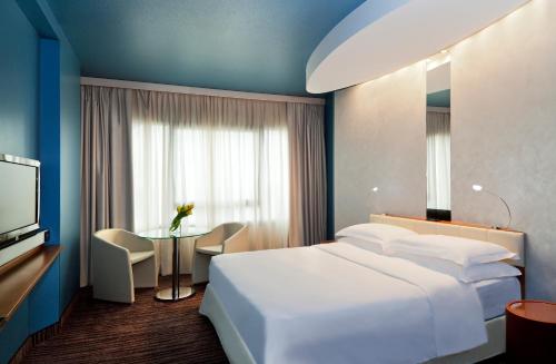 a hotel room with a white bed and a table at Four Points by Sheraton Padova in Padova