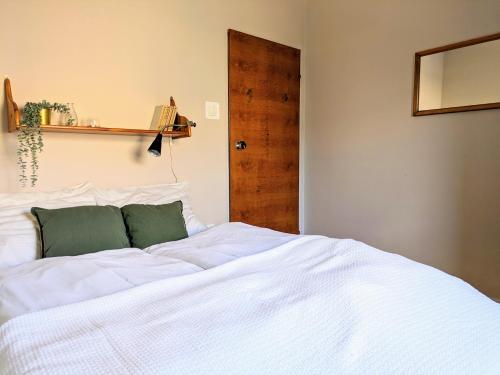 a bedroom with a white bed and a wooden door at SB Apartment with Sauna in Kołobrzeg