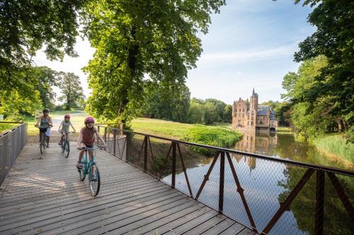 two people riding bikes on a bridge over a river at Vakantiewoning De Gulden Sleutels in Kruibeke