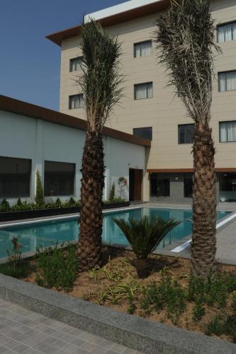 duas palmeiras em frente a um edifício em Crown Park Luxury Hotel em Bhīlwāra