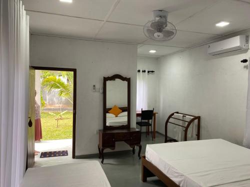Zimmer mit 2 Betten, einem Spiegel und einem Tisch in der Unterkunft Hikka Lotus Garden in Hikkaduwa