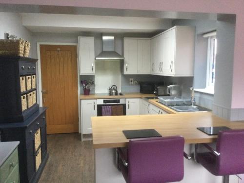 a kitchen with a wooden table and purple chairs at Rowan Berry in Hunstanton