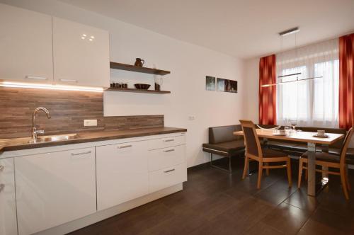 a kitchen with white cabinets and a dining table at Ferienwohnung Sonnenhang in Nußdorf