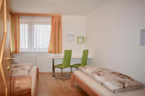 a room with a table and two green chairs at Ferienwohnung Sonnenhang in Nußdorf