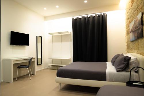 - une chambre avec un lit, un bureau et une télévision dans l'établissement Pane e Pomodoro, à Bari