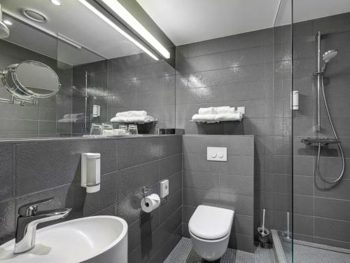 a bathroom with a sink and a toilet and a mirror at Estonia Resort Hotel & Spa in Pärnu