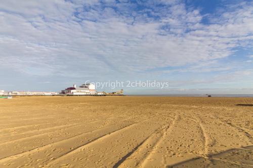 a sandy beach with a building in the background at Beautiful 4 Berth Seaside Apartment On Ground Floor In Hemsby, Ref 99010fh in Great Yarmouth