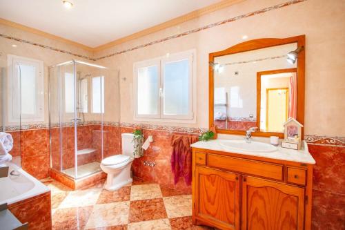 ein Badezimmer mit Toilette, Waschbecken und Spiegel in der Unterkunft Villa Flora - Plusholidays in Calpe