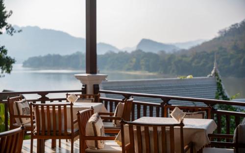 a balcony with tables and chairs and a view of the water at Relaxful Hotel泊岸酒店 in Luang Prabang
