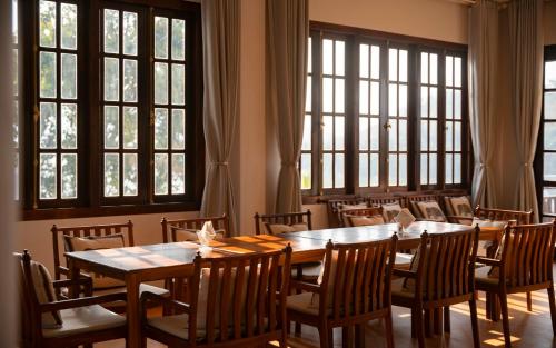 a dining room with tables and chairs and windows at Relaxful Hotel泊岸酒店 in Luang Prabang