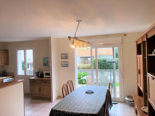 een keuken en een eetkamer met een tafel in een kamer bij Agréable maison ensoleillée avec jardin arboré in Le Château-dʼOléron