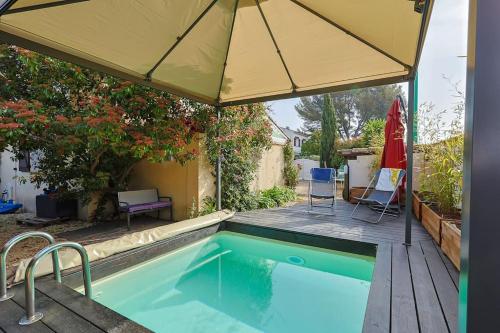 - une piscine avec un grand parasol et des chaises dans l'établissement Superbe maison élégante proche mer, au Pradet