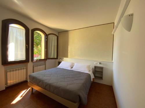 ein Schlafzimmer mit einem Bett und zwei Fenstern in der Unterkunft Unabhaengige Wohnung in Sirmione mit Eigener Terrasse in Sirmione