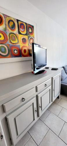 - une télévision installée au-dessus d'une table dans l'établissement Le Petit Nénuphar plage et commerces à 400 m, au Grau-du-Roi