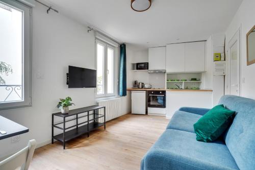 un salon avec un canapé bleu et une cuisine dans l'établissement TOP 2 pièces tout équipé avec WIFI proche Paris - R7, à Montreuil