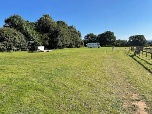 een veld met een park met een busje in de verte bij Converted barn one bedroom studio glamping in Horspath