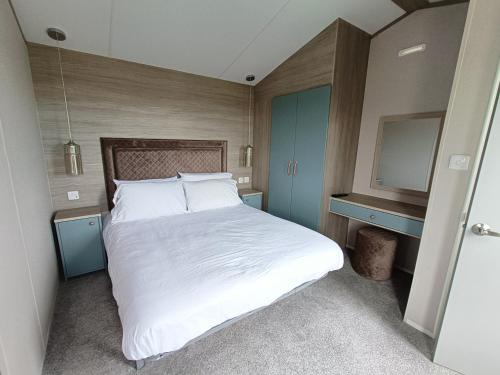 um quarto com uma grande cama branca e uma televisão em The Getaway Luxury Carvan in Bude em Poughill