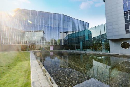 a glass building with a reflecting pool in front of it at UrCove by Hyatt Shanghai Pudong East in Shanghai