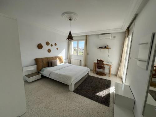 ein weißes Schlafzimmer mit einem Bett und einem Fenster in der Unterkunft appartement 14 in Chott Meriem
