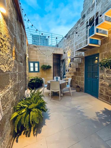 a patio with a table and chairs and a blue door at Ta Pietru in Żabbar