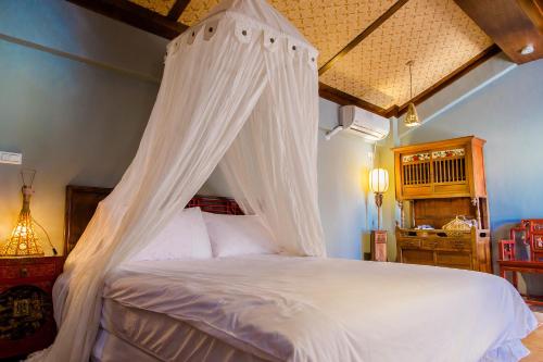 a bedroom with a white bed with a canopy at Murraya Paniculata Villa in Magong