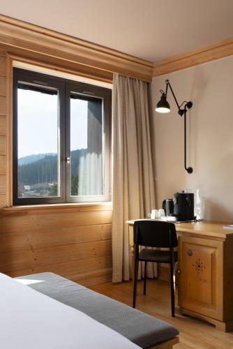 a hotel room with a table and a window at Hôtel Restaurant Spa Les Jardins De Sophie in Xonrupt-Longemer