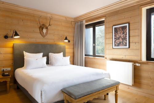 una camera con un grande letto bianco e una panca di Hôtel Restaurant Spa Les Jardins De Sophie a Xonrupt-Longemer