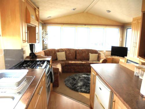 a living room with a couch and a kitchen at 6 Berth Sealands Ingoldmells Free WIFI Westmorland SL in Ingoldmells