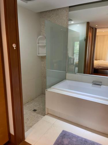 a bathroom with a tub and a large mirror at WERT in Phuket Town