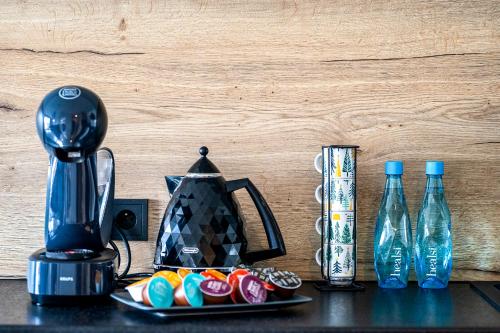 Apartament EcoPure Tychy في تيخي: غلاية الشاي والحلوى على طاولة مع زجاجات المياه
