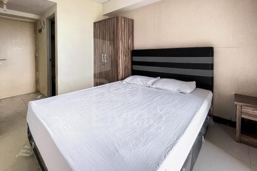 um quarto com uma cama grande e lençóis brancos em RedLiving 19 Avenue Apartment by RH Room em Tangerang