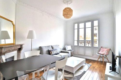 ein Wohnzimmer mit einem Tisch und einem Sofa in der Unterkunft Escale Urbaine: Confort & Métro à 2 Pas in Saint-Ouen