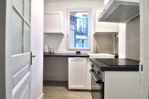 eine Küche mit weißen Schränken und einem Fenster in der Unterkunft Escale Urbaine: Confort & Métro à 2 Pas in Saint-Ouen