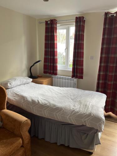 a bedroom with a bed and a chair and a window at The Cabin in Hockham
