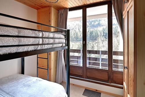 een slaapkamer met een stapelbed en een groot raam bij Le Cocoøn - Appt vue montagne in La Bresse